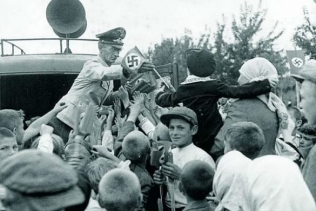 Работник рейхсминистерства оккупированных территорий раздает флажки со свастикой киевлянам во время празднования второй годовщины вступления в город немецких войск. 19 сентября 1943-го. Через полтора месяца в Киев вернется советская власть. 