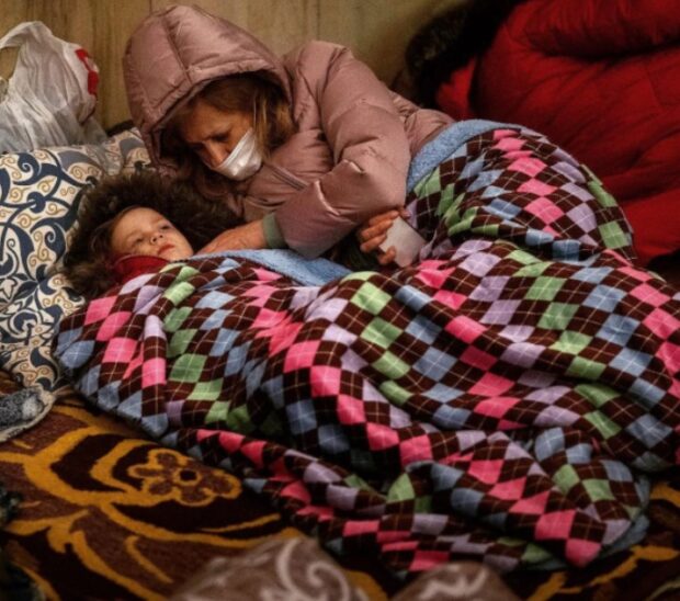 Київ, 24 лютого, перший день війни. Жінка з дитиною ховаються в бомбосховищі від російських обстрілів.

